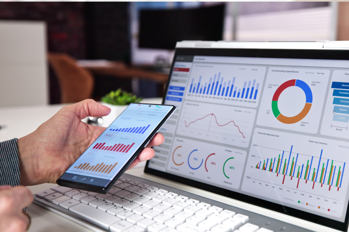 person looking at analytical graphs on smartphone and computer
