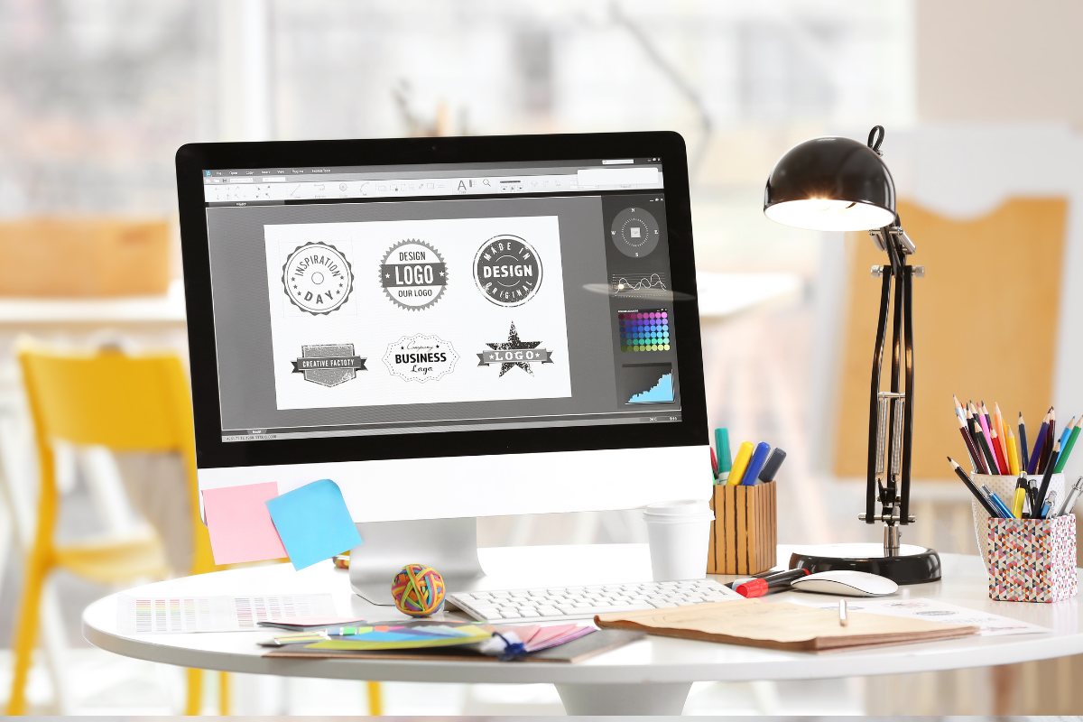 desk with computer showing different logo designs